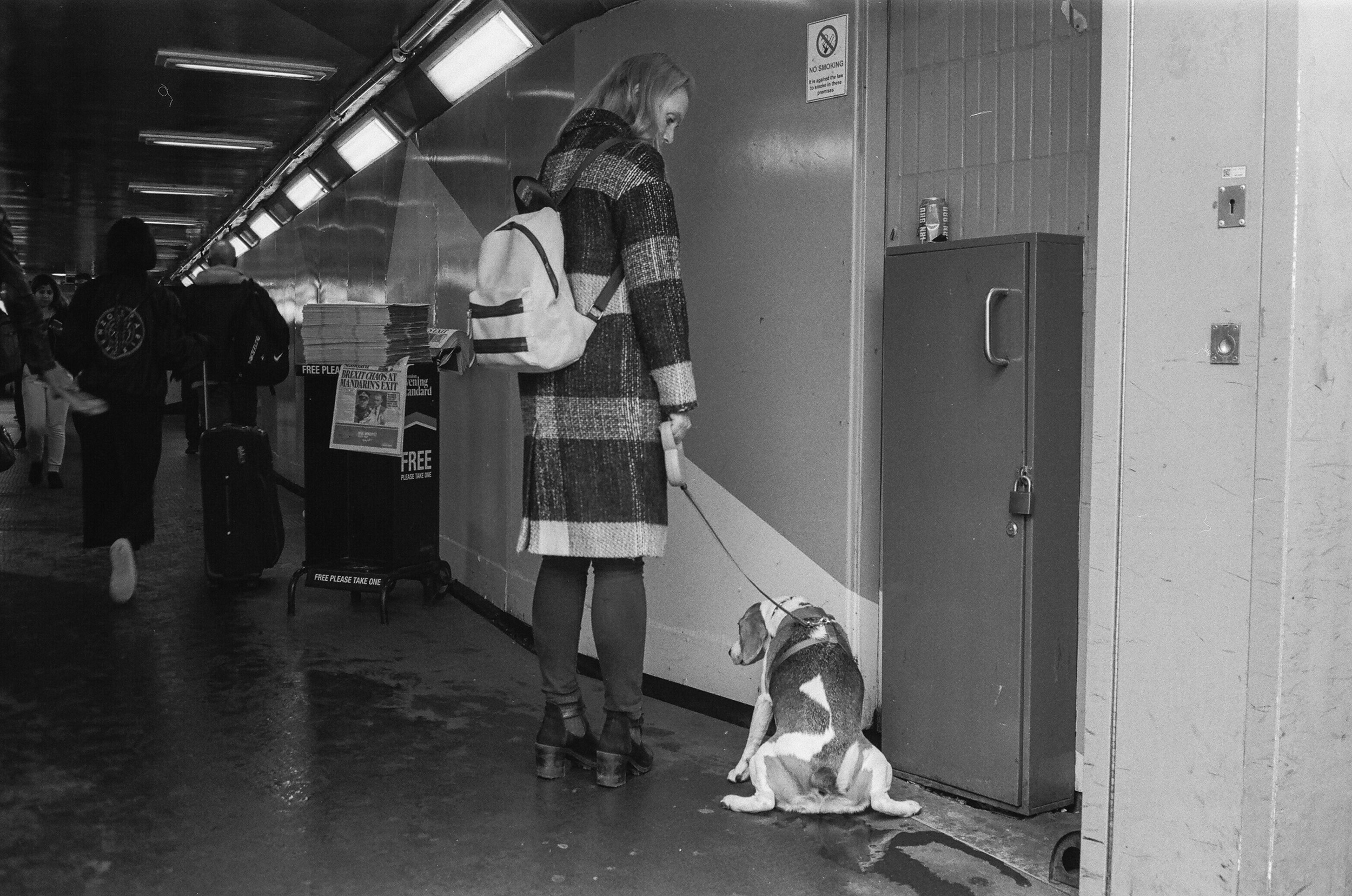 A-BLACK-AND-WHITE-FILM-PHOTO-OF-A-WOMAN-AND-HER-DOG-PEEING-IN-THE-ENTRANCE-OF-A-TUBE-STATION-LONDON-