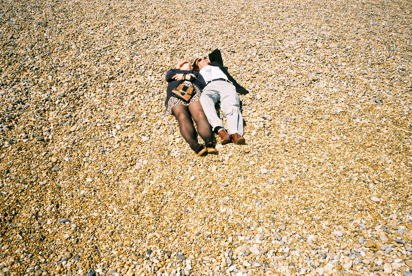 A-COUPLE-NAP-ON-A-PEBBLE-BEACH-FULLY-CLOTHED-IN-BRIGHTON-UK
