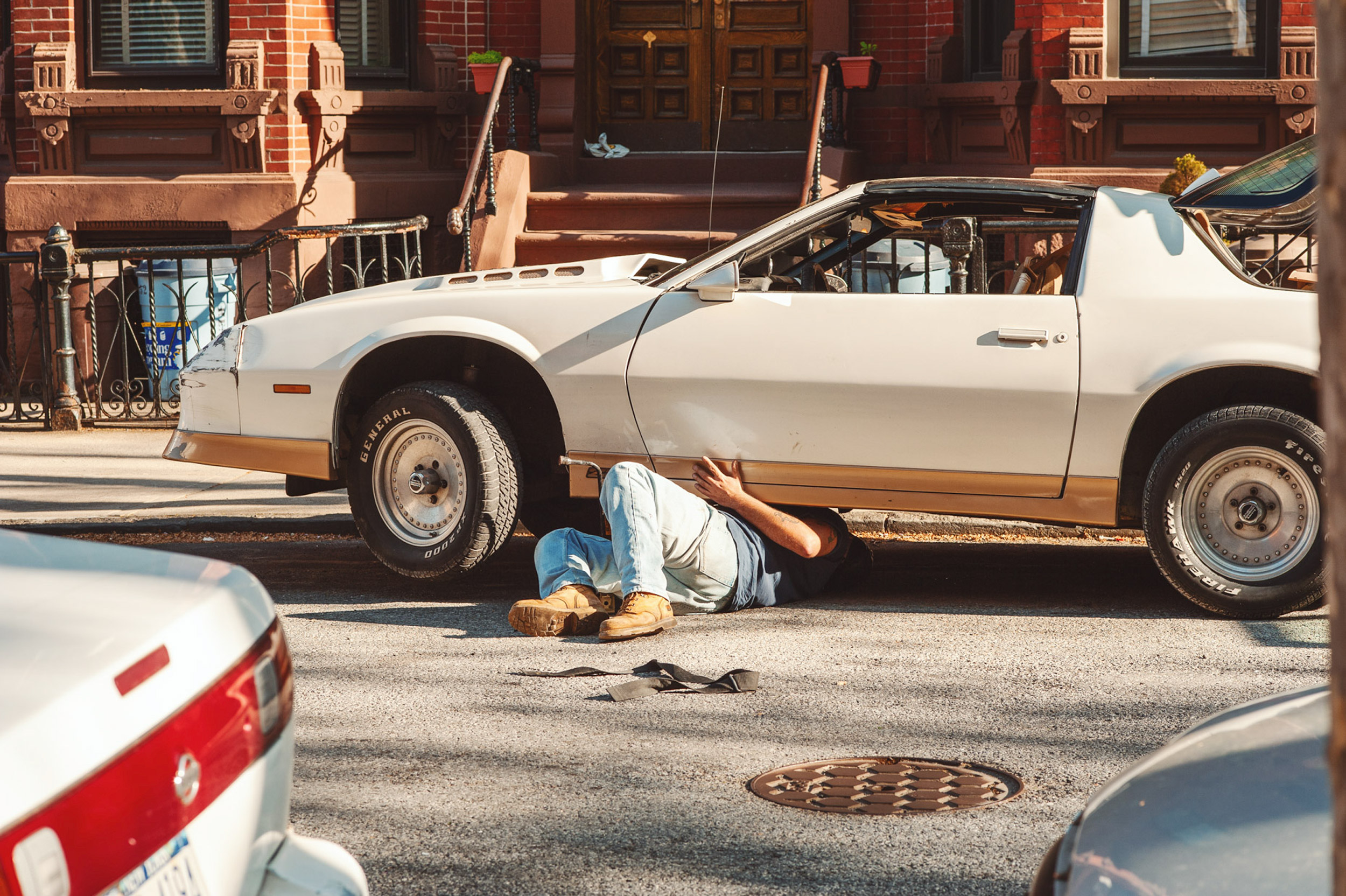 A-MECHANIC-UNDER-HIS-VINTAGE-SPORTS-CAR-IN-BROOKLYN-NEW-YORK