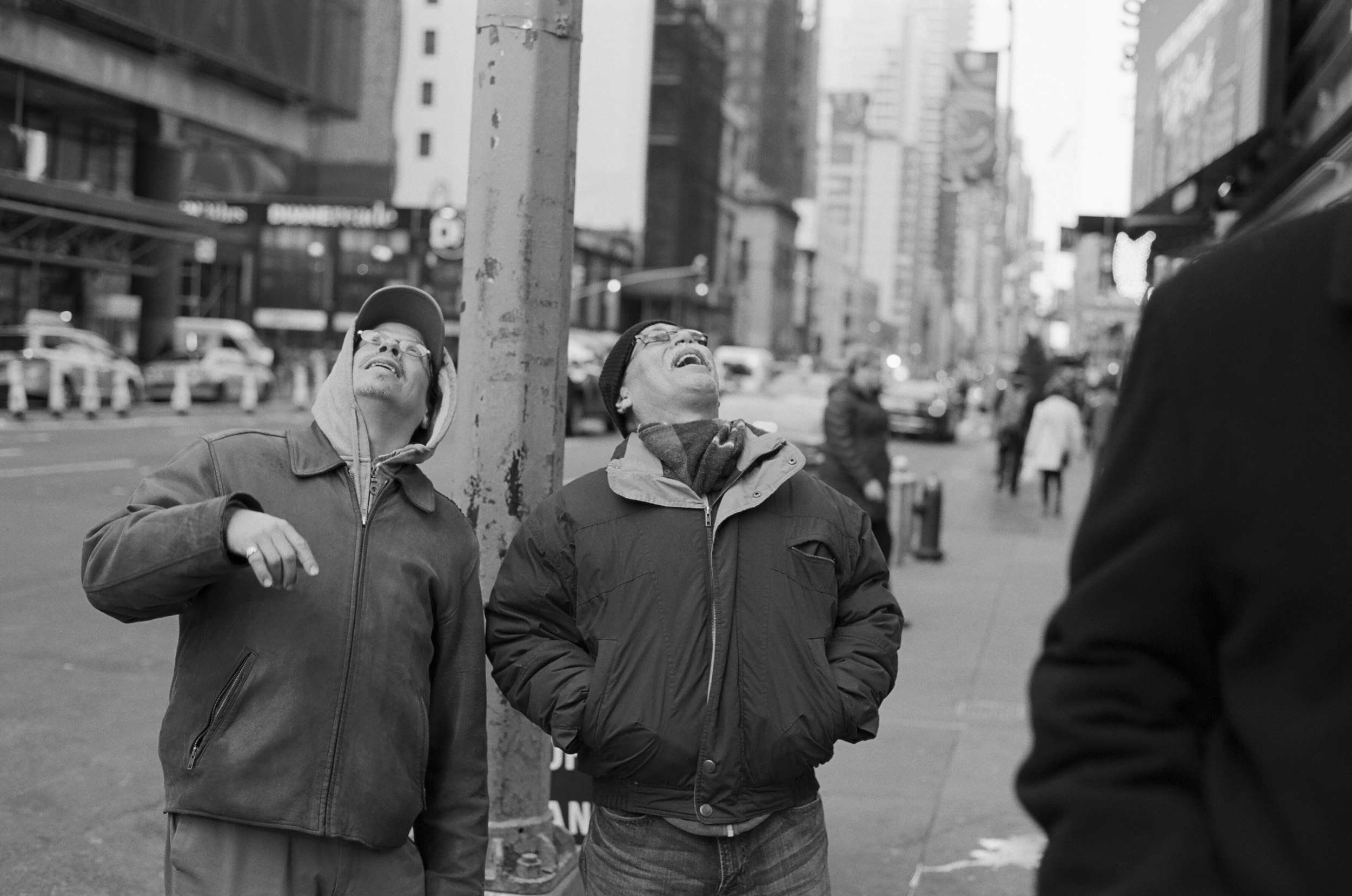 A-STREET-PHOTO-OF-TWO-MEN-LOOKING-UP-AND-LAUGH-IN-MANHATTAN-NEW-YORK