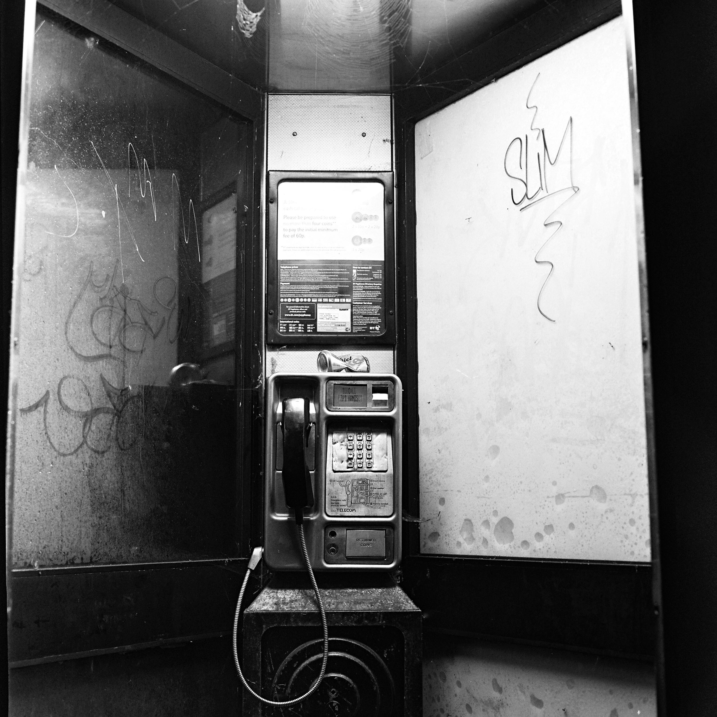 A GRITTY AND NEGLECTED PHONE BOOTH IN ENGLAND AT NIGHT 