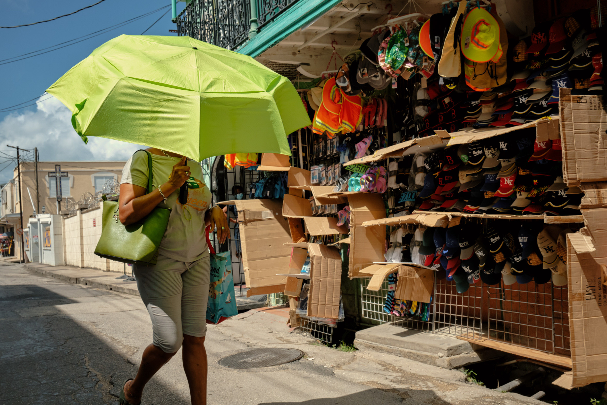 A WOMAN USES HER UMBRELLA TO SHELTER FROM THE HOT WEST INDIES SUN