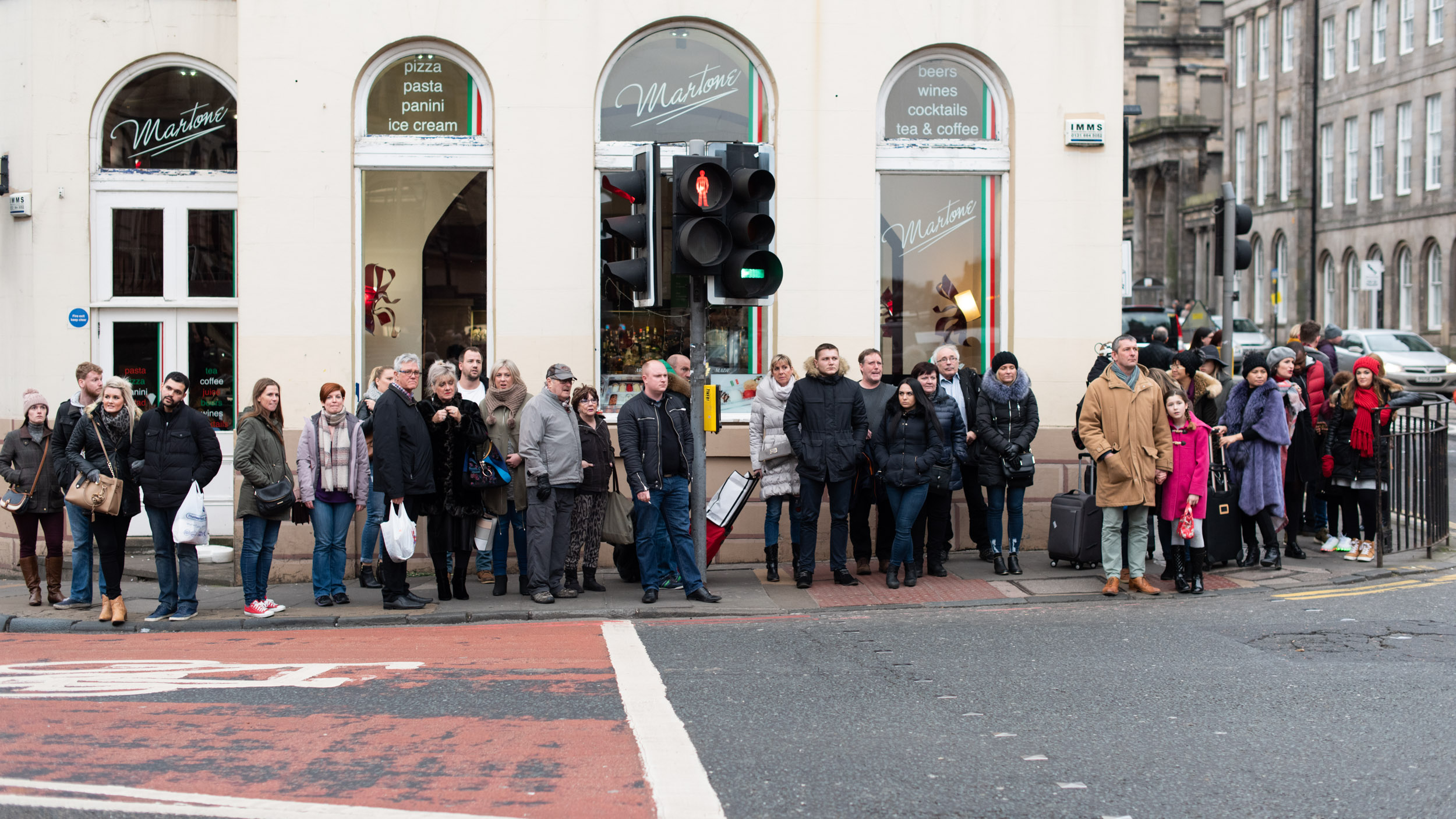 A CROWD OF PEOPLE WAIT A CROSSING IN EDINBURGH SCOTLAND