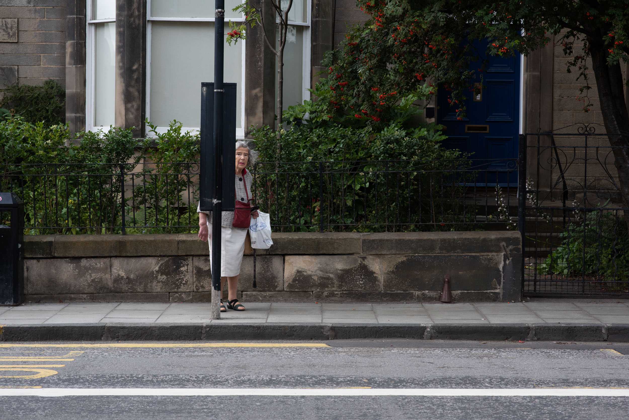 AN OLD WOMAN WAITS A BUS STOP IN EDINBURGH SCOTLAND