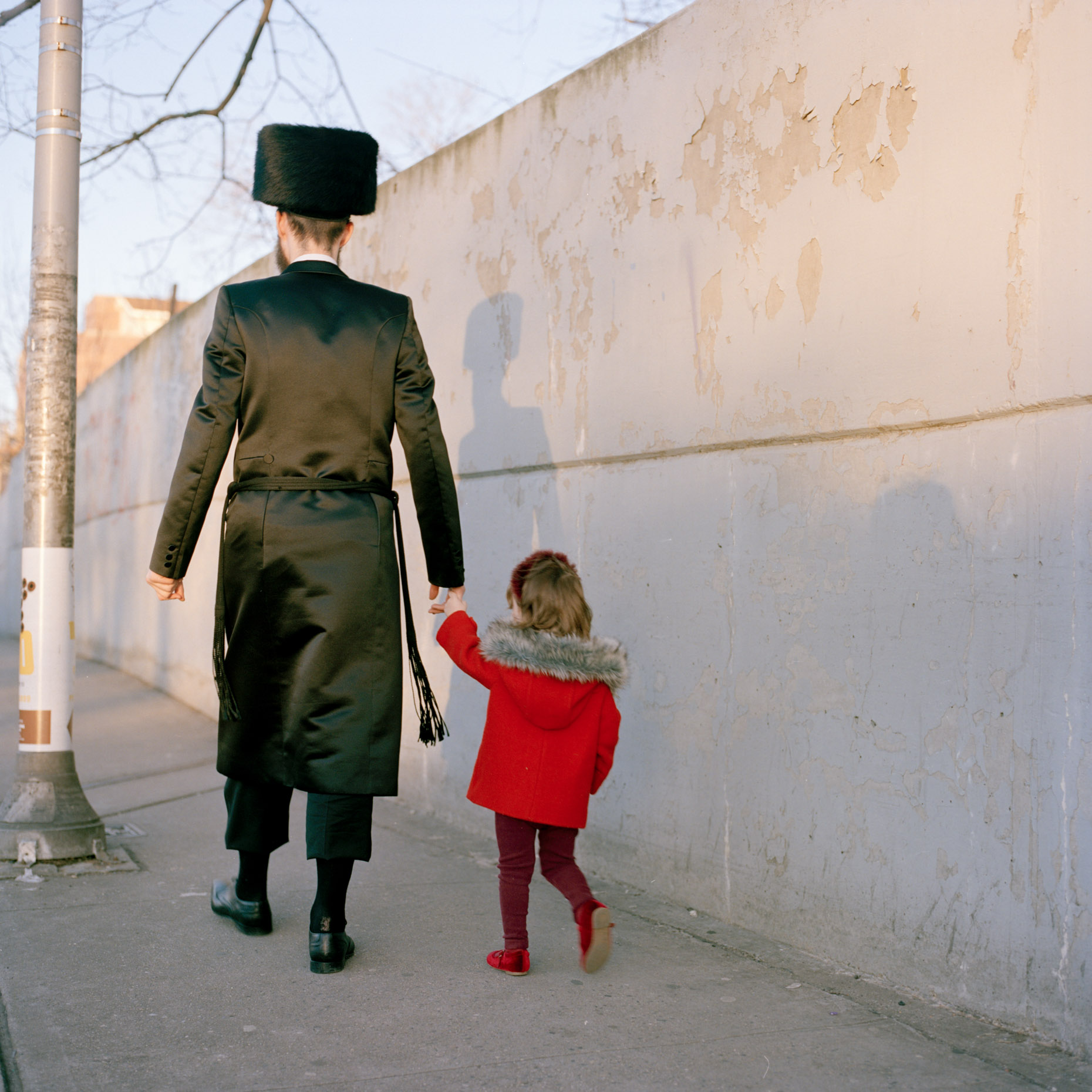 An Orthadox Jewish man holds his daughters hand as he walks through Borough Park, Brooklyn, New York City